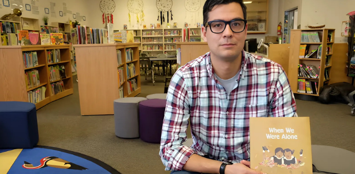 David A. Robertson poses with his picture book When We Were Alone, which was illustrated by Julie Flett