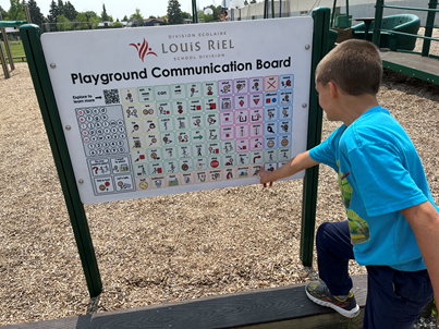 Child pointing at wwing on playground communications board