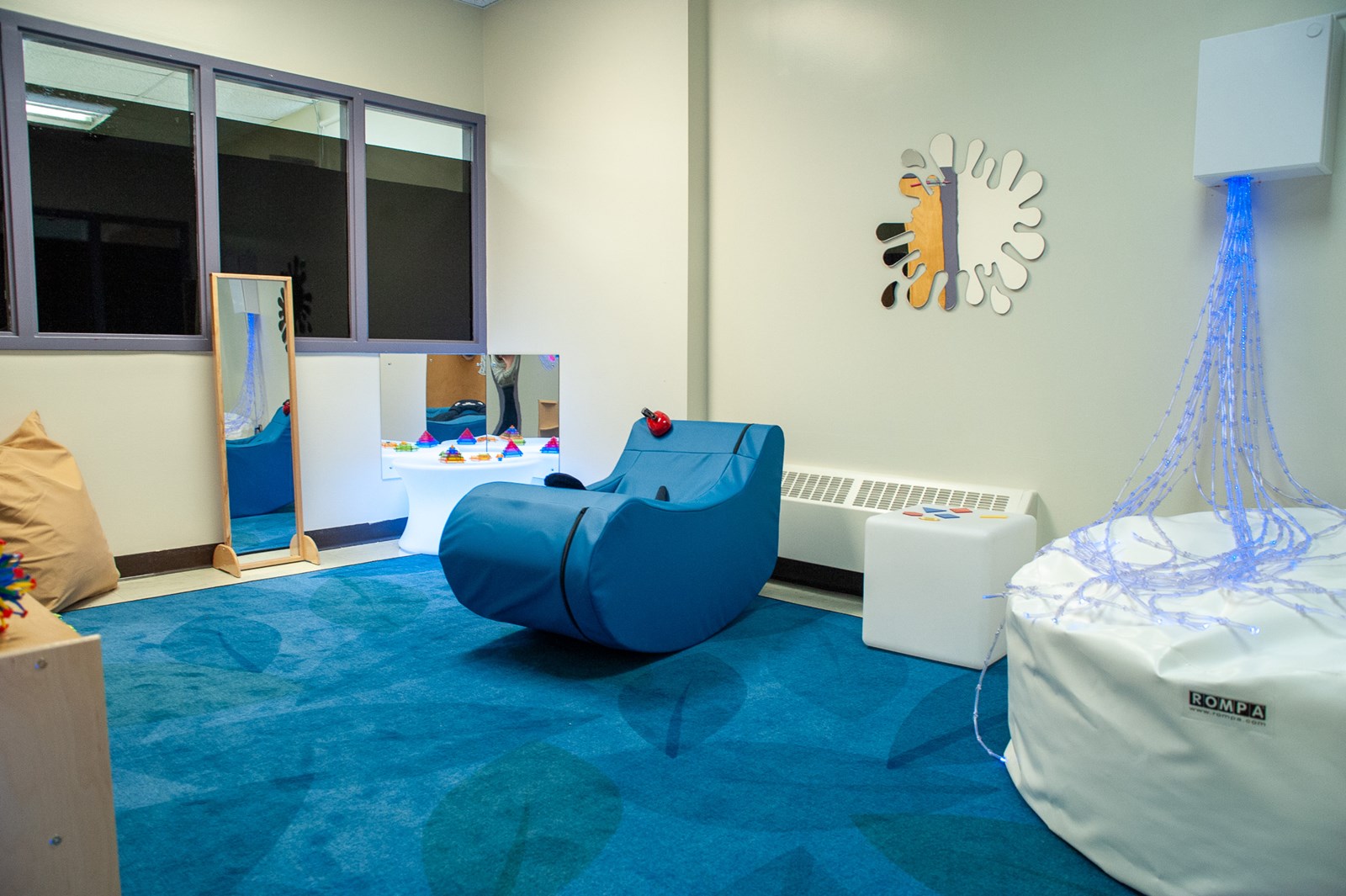 Sensory room with soft carpet, hanging LED strand, and chair