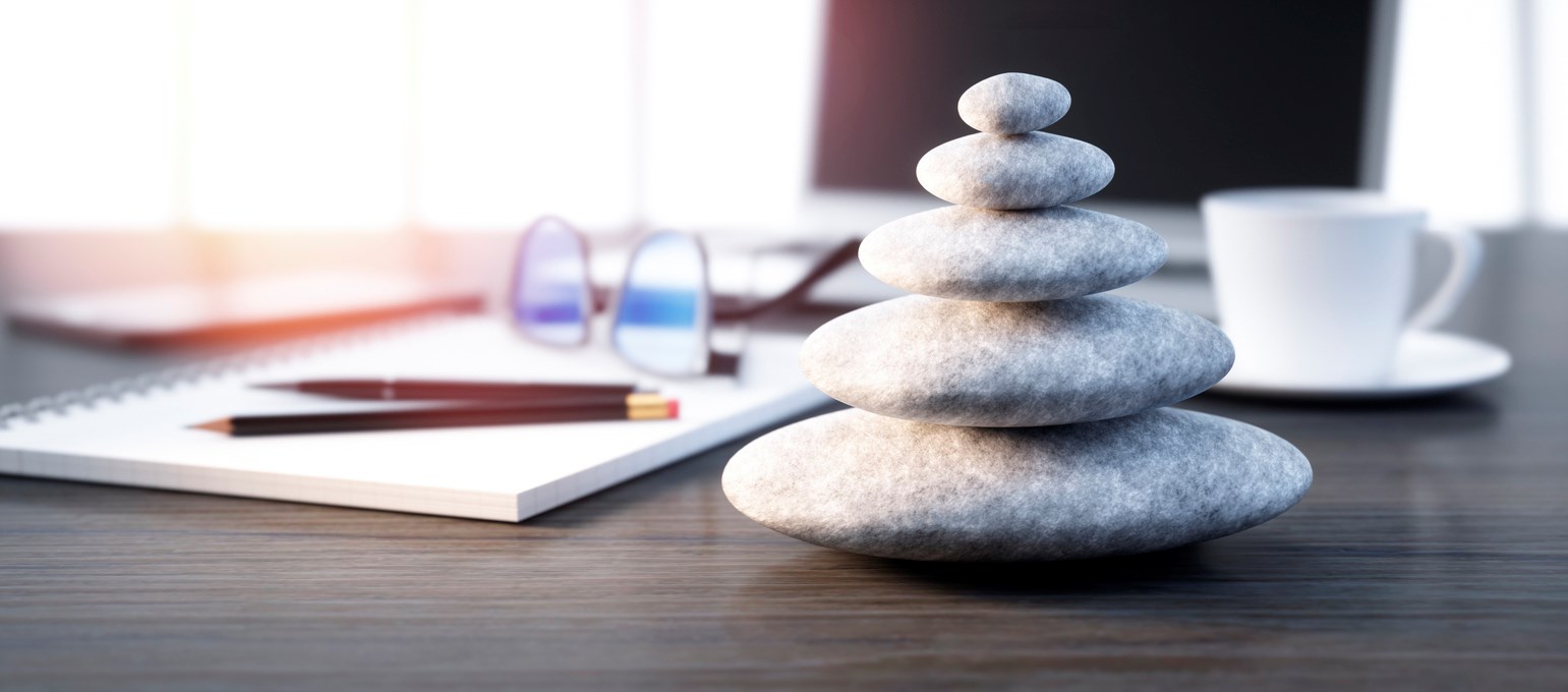 Rocks stacked neatly on table with writing pad and coffee cup