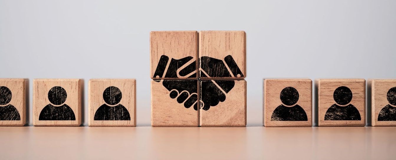 wooden blocks with people icons and handshake icon printed on them.