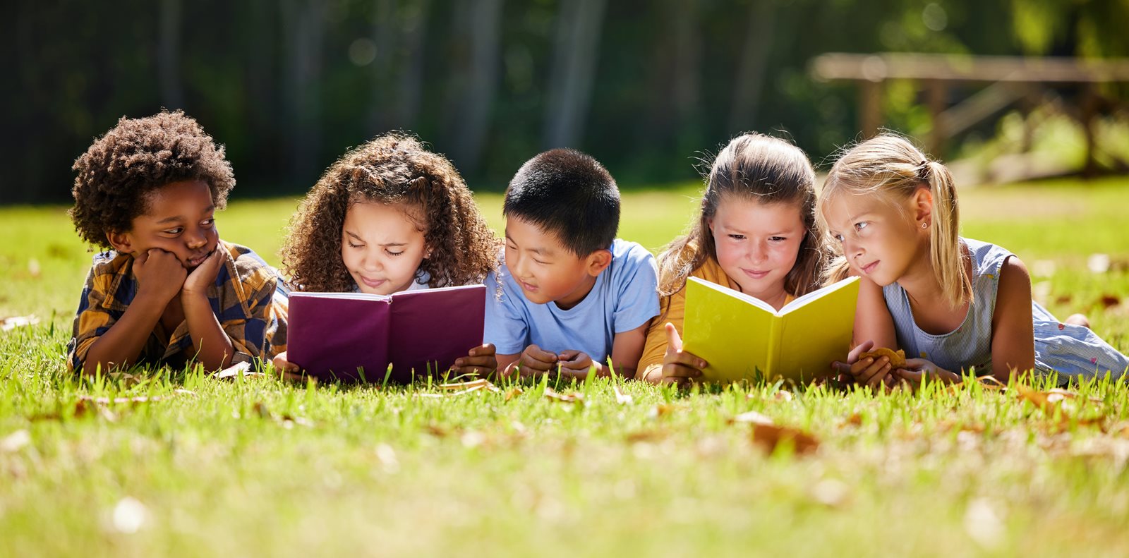 Shot of a group of kids reading a book outside stock photo